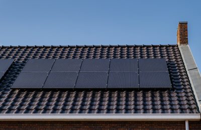 Newly build houses with solar panels attached on the roof against a sunny sky Close up of new building with black solar panels. Zonnepanelen, Zonne energie, Translation: Solar panel, , Sun Energy